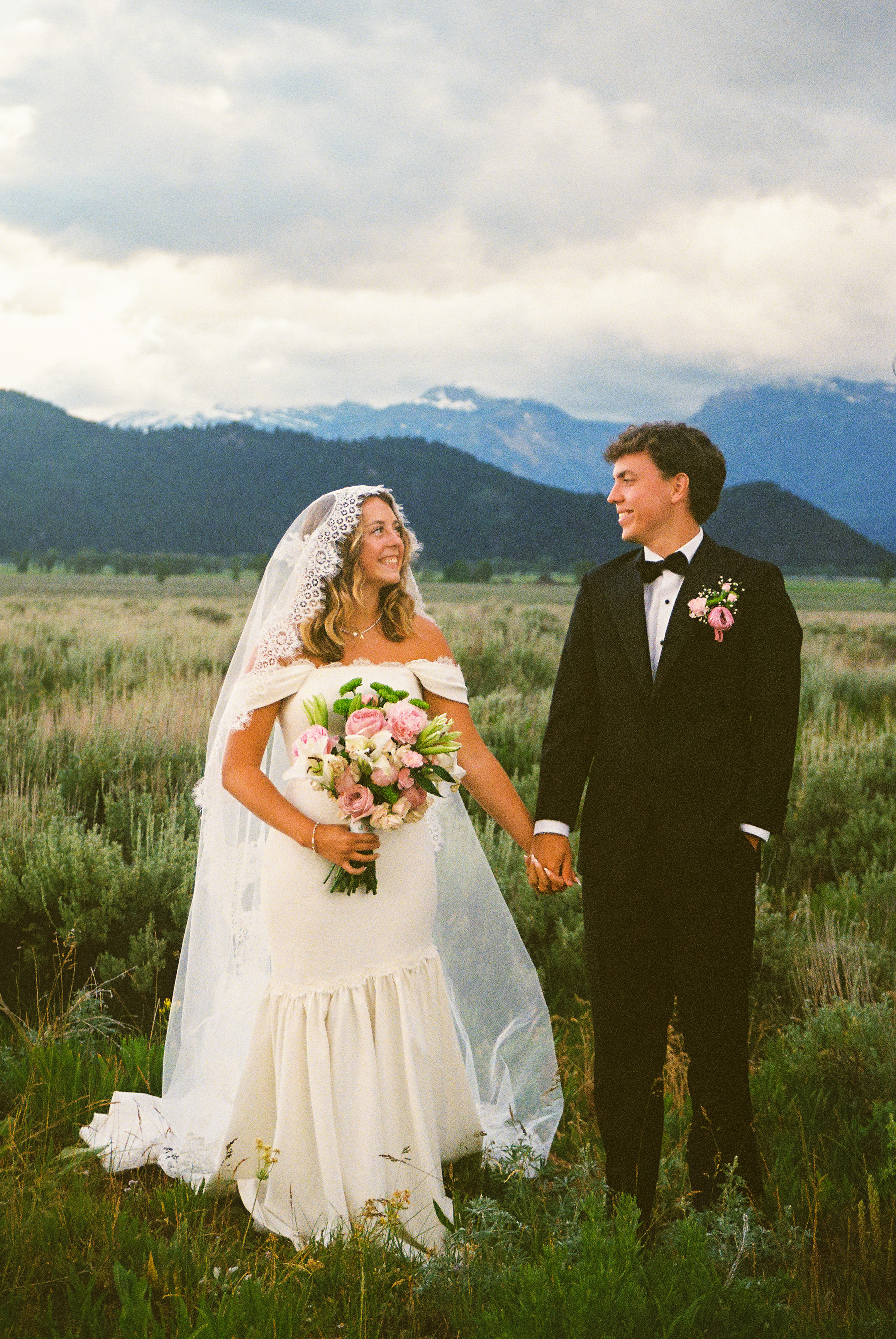 Bride and groom smiling together beneath the mountains, photographed by Katherine