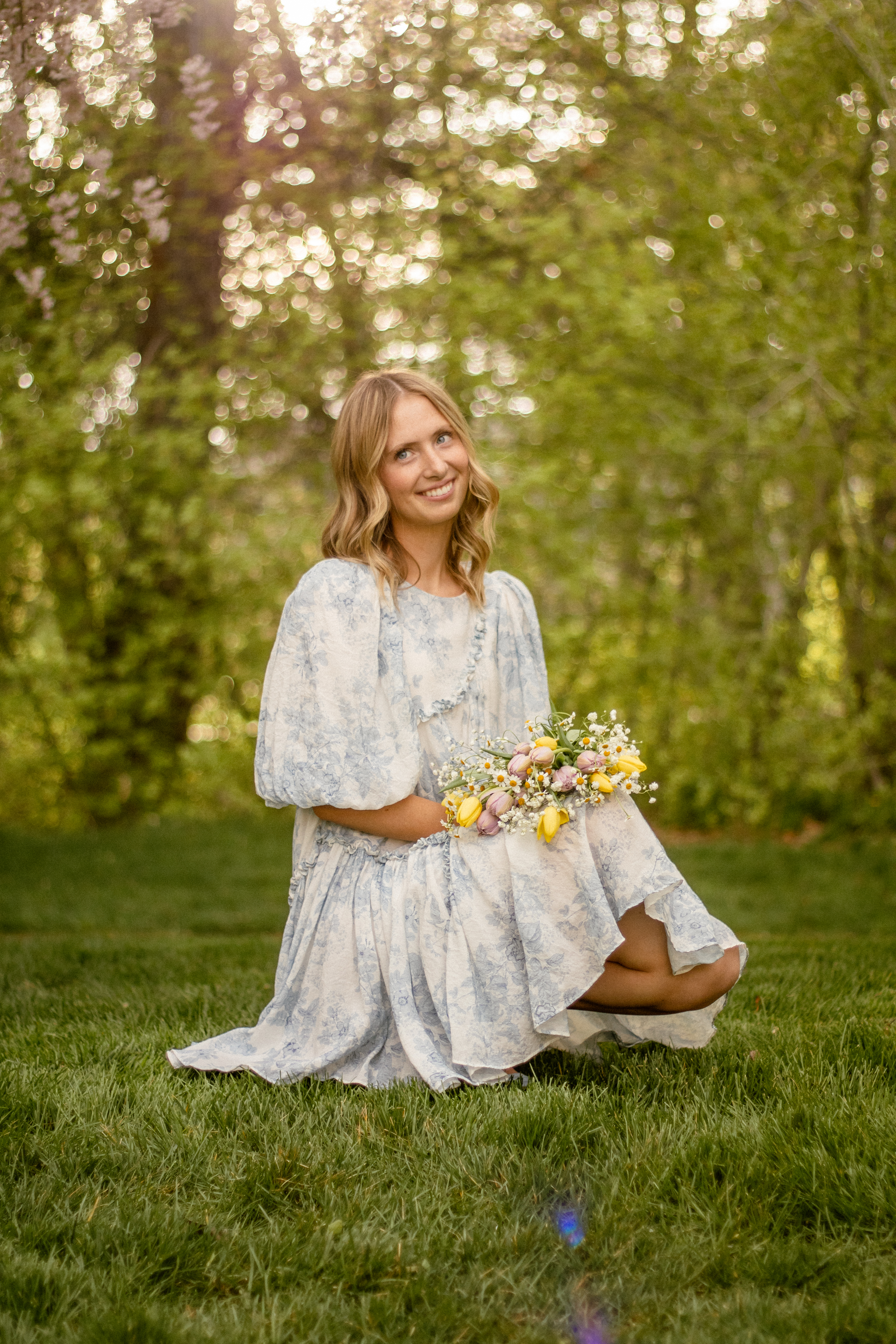 Senior portrait with flowers in a sunlit garden, photographed by Katherine